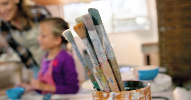 Paintbrushes in Focus, Child Painting in Background - Download Free Stock Images Pikwizard.com