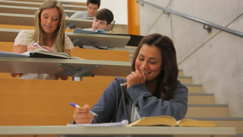 Engaged College Students Exchanging Notes in Lecture Hall