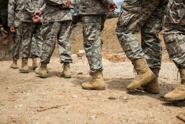 This image shows a group of military soldiers marching in a training session at boot camp. They are wearing camouflage uniforms and combat boots, demonstrating teamwork and discipline. This image can be used for articles or content related to military training, teamwork, discipline, or defense forces.