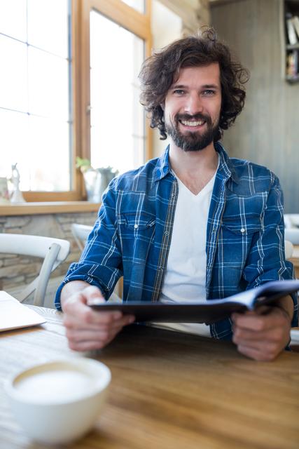 Portrait of smiling man holding menu in coffee shop