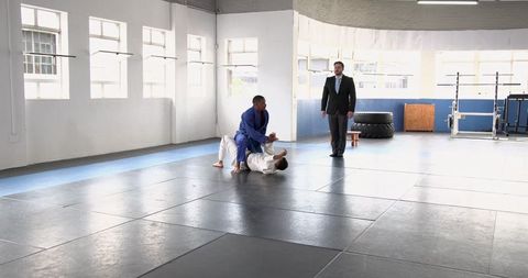 Martial artists sparring in spacious gym with instructor