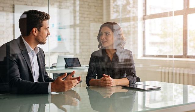 Business professionals discussing strategy in modern glass office during daylight meeting