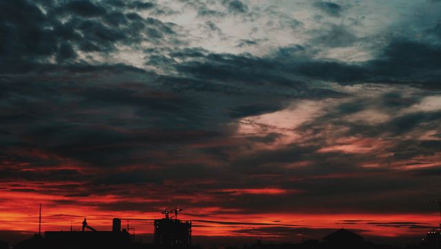 Vibrant colors of a sunset sky casting dramatic lighting over urban silhouttes. Ideal for backdrops, travel blogs, urban exploration content, and website headers that require atmospheric and striking visuals.