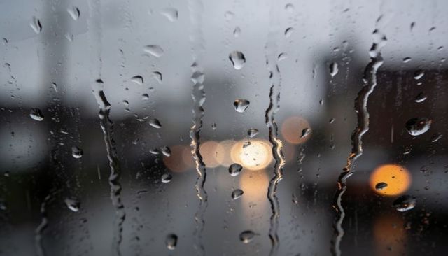 Dripping Raindrops on Window Glass Revealing Headlight Bokeh and Wet Street Glow