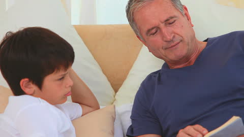 Grandfather Reading Book with Grandson at Home
