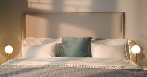 Minimalist Modern Bedroom Featuring Upholstered Headboard and Teal Accent Pillow