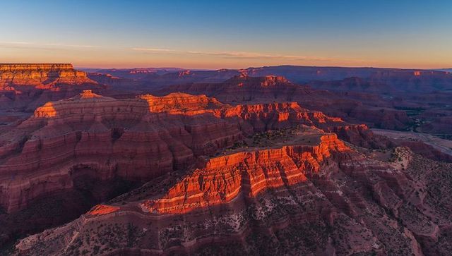 Sunrise lighting red rock canyon mesas and layered cliffs panoramic desert vista