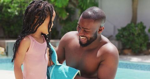 Happy Father Drying Daughter with Towel by Poolside