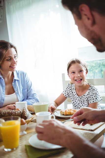 Family enjoying breakfast together, creating a joyful atmosphere. This image can be used for promoting healthy family meals, family-oriented products, or advertisements emphasizing togetherness.