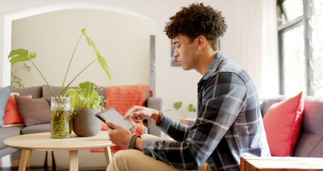 Young Man Browsing Tablet in Cozy Living Room - Download Free Stock Images Pikwizard.com