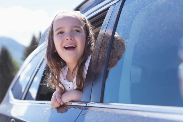 Cute girl looking out of the car window on a sunny day