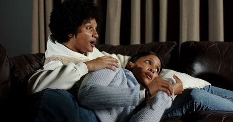 Surprised couple lounging on sofa in cozy home