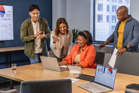 Multicultural team celebrating successful presentation in modern conference room