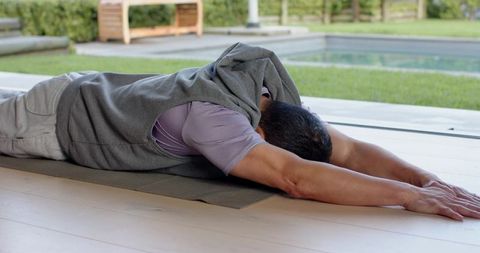 Senior man doing relaxing yoga stretch on outdoor deck