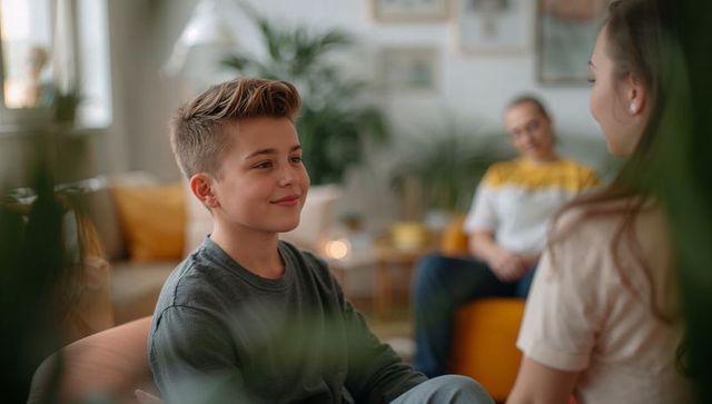 Teen boy smiling while talking to sister in cozy family living room with plants