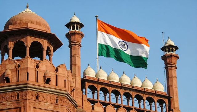 Waving indian tricolor over red fort sandstone domes and minarets
