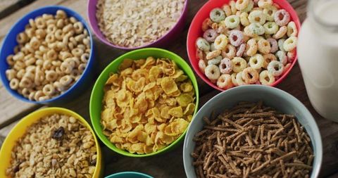 Displaying colorful cereal bowls on rustic wooden table with milk bottle