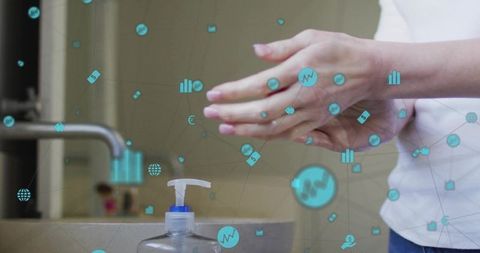 Mid-adult woman applying hand sanitizer at home sink with digital health icons for hygiene