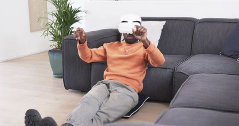African american man wearing vr headset on living room floor experiencing immersive home tech