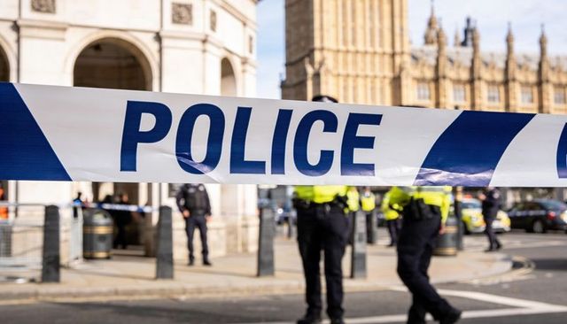 Police tape blocking street while officers patrolling historic gothic government buildings