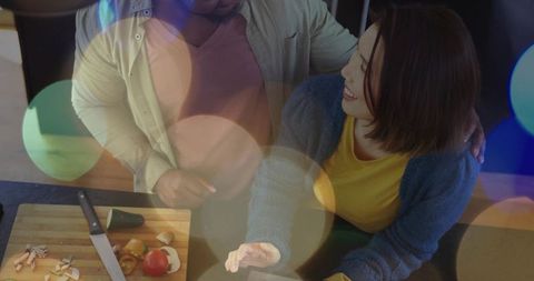 Couple cooking together in cozy kitchen using tablet while chopping fresh vegetables
