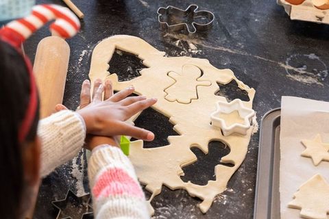 Child cutting christmas cookie shapes from rolled dough baking festive cookies with cutters