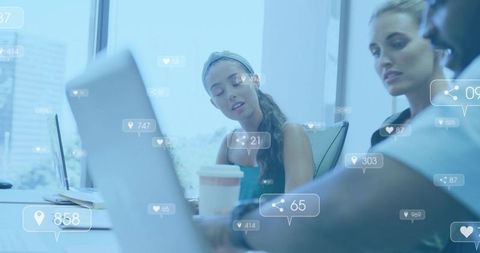 Team Collaborating on Laptop with Social Media Alerts Overlays in Modern Glass Office