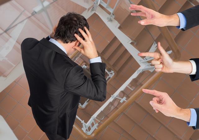 This image depicts a businessman in a suit standing in a staircase, holding his head in distress while multiple hands point at him. It is ideal for illustrating concepts related to workplace stress, pressure, anxiety, and mental health in corporate settings. Useful for articles, blogs, and presentations on stress management, corporate culture, and mental well-being.