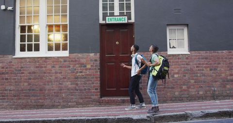 Backpacking Friends Exploring Urban Streets Seeking Hostel