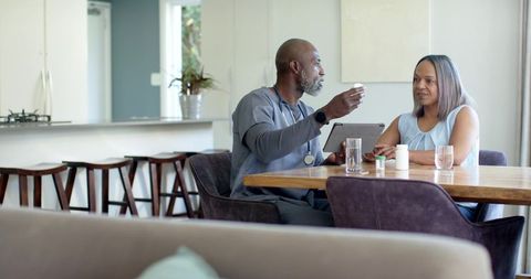African american nurse conducting home medication consultation with middle-aged patient