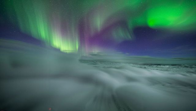 Aurora Borealis Dancing Over Snow-Covered Arctic Plain Under Starry Night Sky