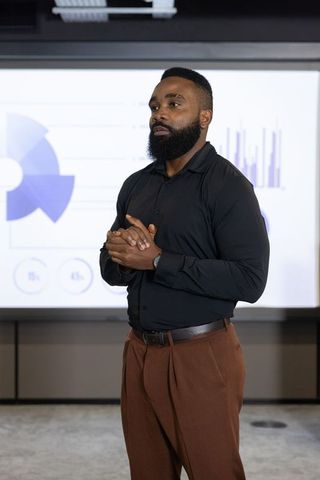 African american presenter in business meeting with projected charts