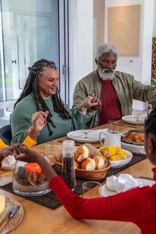 African american couple holding hands at family dinner table sharing warm sunlit meal
