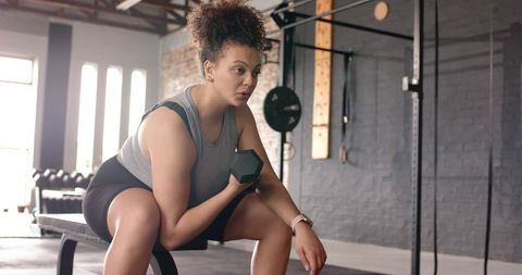 Woman lifting dumbbell on bench in industrial gym, strength training and focus