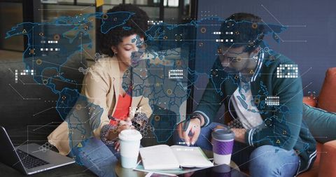 Professionals collaborating over analytics with laptop, coffee and notes in modern lounge