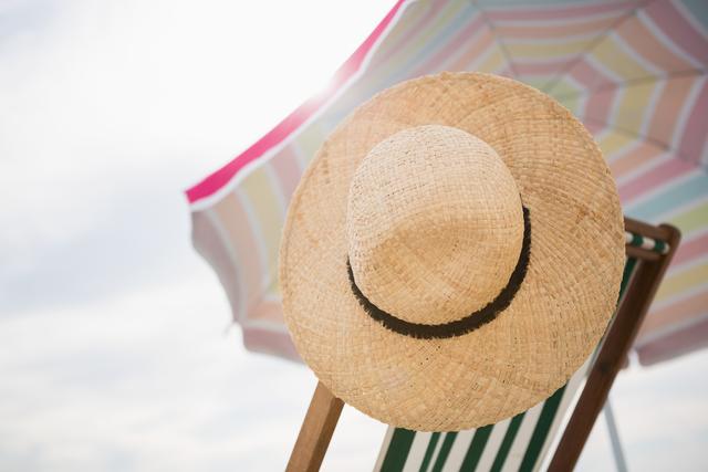 Straw hat and beach chair kept under a beach umbrella