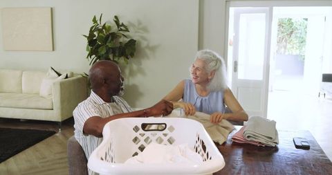 Happy Senior Couple Folding Laundry at Home