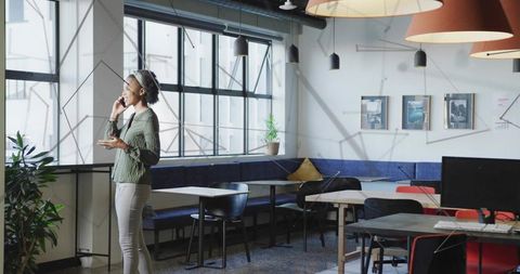 Confident Professional Woman Holding Smartphone in Modern Open Office