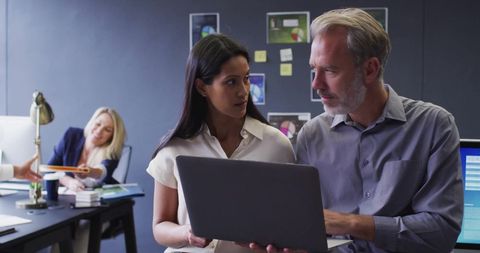 Diverse Professional Team Analyzing Data on Laptop in Modern Office