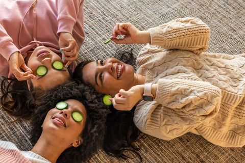 Friends enjoying at-home spa night with cucumber eye masks and cozy sweaters