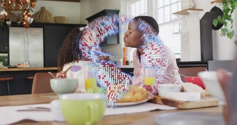 Senior man leaning to kiss child during breakfast with holographic augmented reality globe overlay