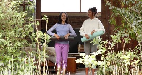 Female Friends Holding Yoga Mats on Rustic Wooden Porch