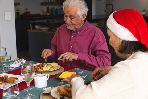 Senior Couple Enjoying Holiday Meal Together Around Festive Table