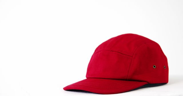 A red baseball cap is positioned against a white background, with copy space. Its vibrant color and classic design make it a versatile accessory for casual outfits.