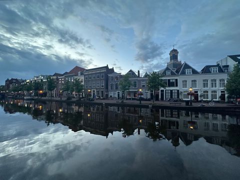 Canal reflecting historic Dutch houses and church tower at dusk