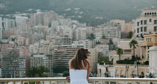 Rear view of a caucasian woman standing in the balcony enjoying the view of cityscape. travel and vacation concept