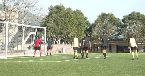 Youth soccer players competing for goal on school field