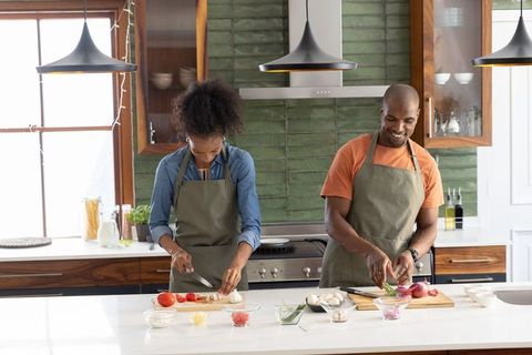 Couple cooking at modern kitchen island chopping vegetables and preparing healthy meal