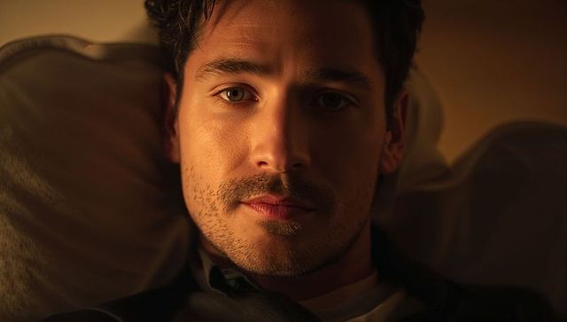 Intimate low-key portrait of thoughtful man lying in bed, cinematic moody closeup lighting