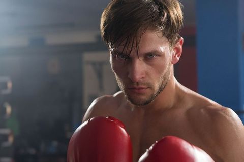 Focused Male Boxer in Gym Holding Red Gloves